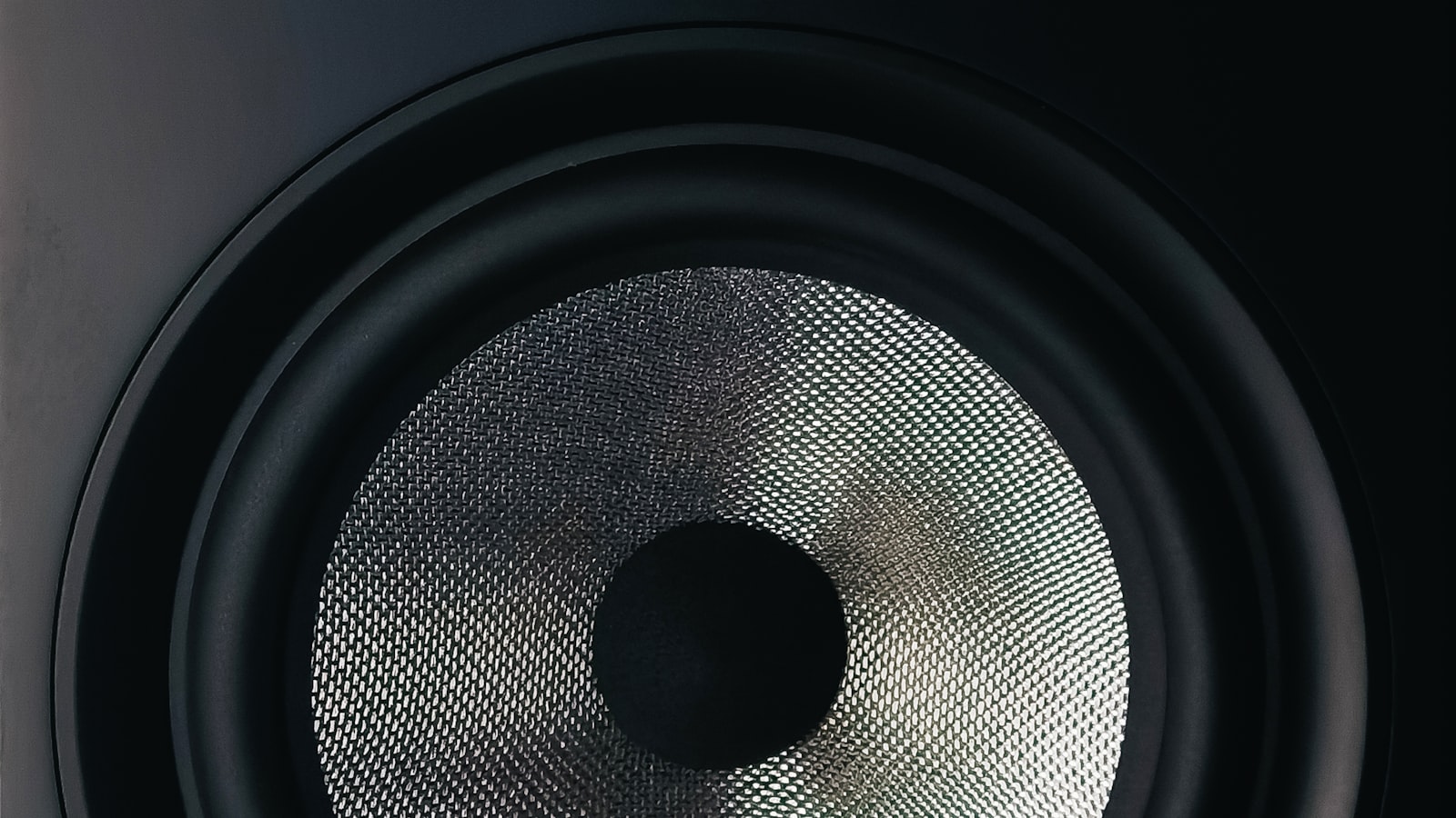 Black and gray bookshelf speaker on a wooden table, the kind of player Music Assistant drives over the network